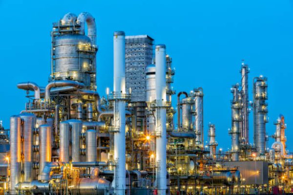 A large, modern petrochemical plant at dusk in industrial district near Rotterdam, Netherlands, Benelux, Europe. Many chimneys, tanks, distillation towers and other installations are visible against blue sky. 50 megapixel HDR image taken with Canon EOS 5Ds, digital blending technique, long exposure with tripod.